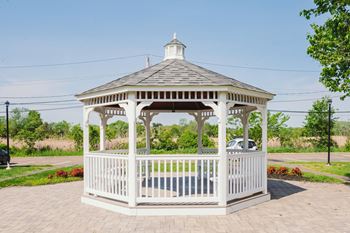 A white gazebo with a cupola and a brick sidewalk